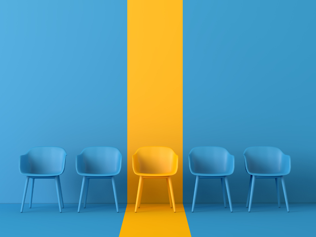 Yellow chair standing out among blue chairs, representing differentiation, innovation, and competitive advantage in AI strategy.