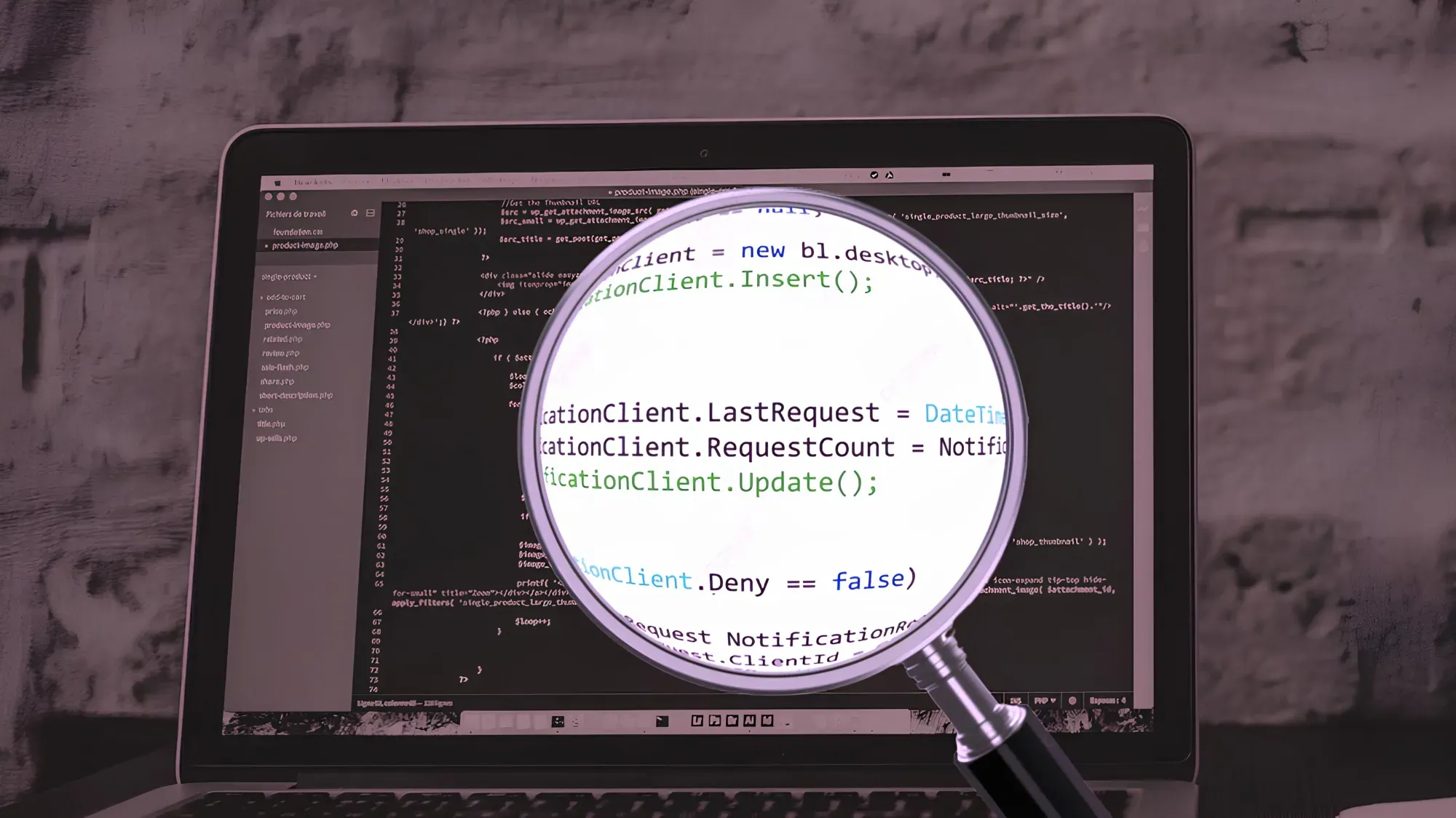 Black-and-white image of a laptop displaying code, with a magnifying glass enlarging text. Conveys focus on software development and coding details.